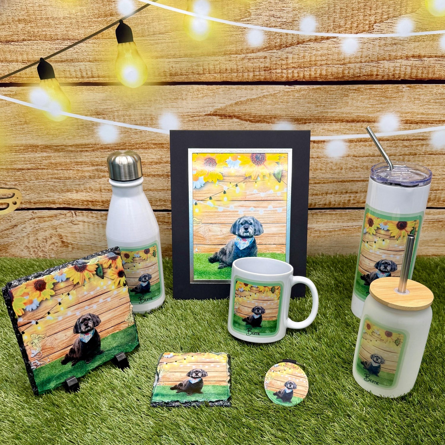 Collection of dog-themed products including a mug, bottle, and coasters on grass with a wooden background.