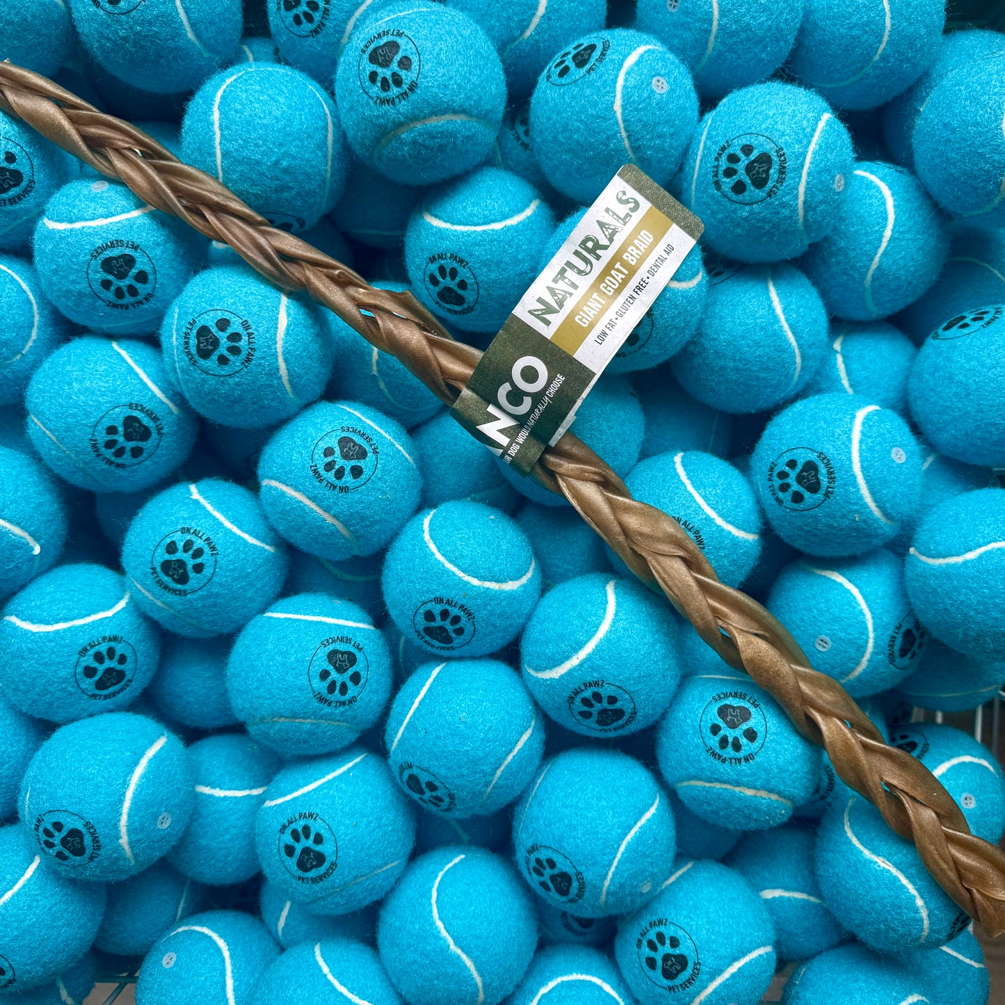 Blue tennis balls with paw prints and a brown rope on a blue background