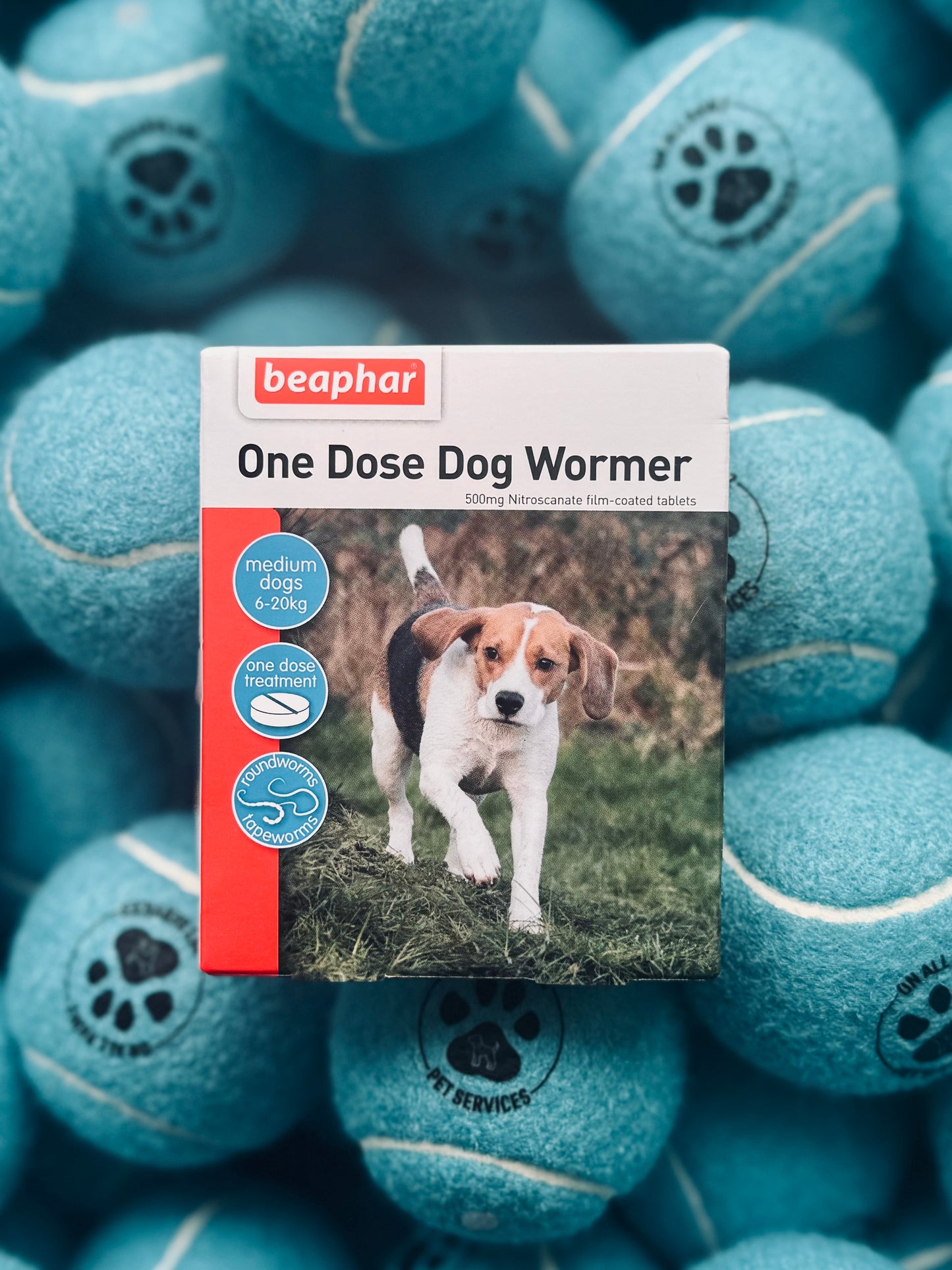 Packaging of Beaphar One Dose Dog Wormer with a picture of a dog on the front, placed on a background of blue tennis balls.
