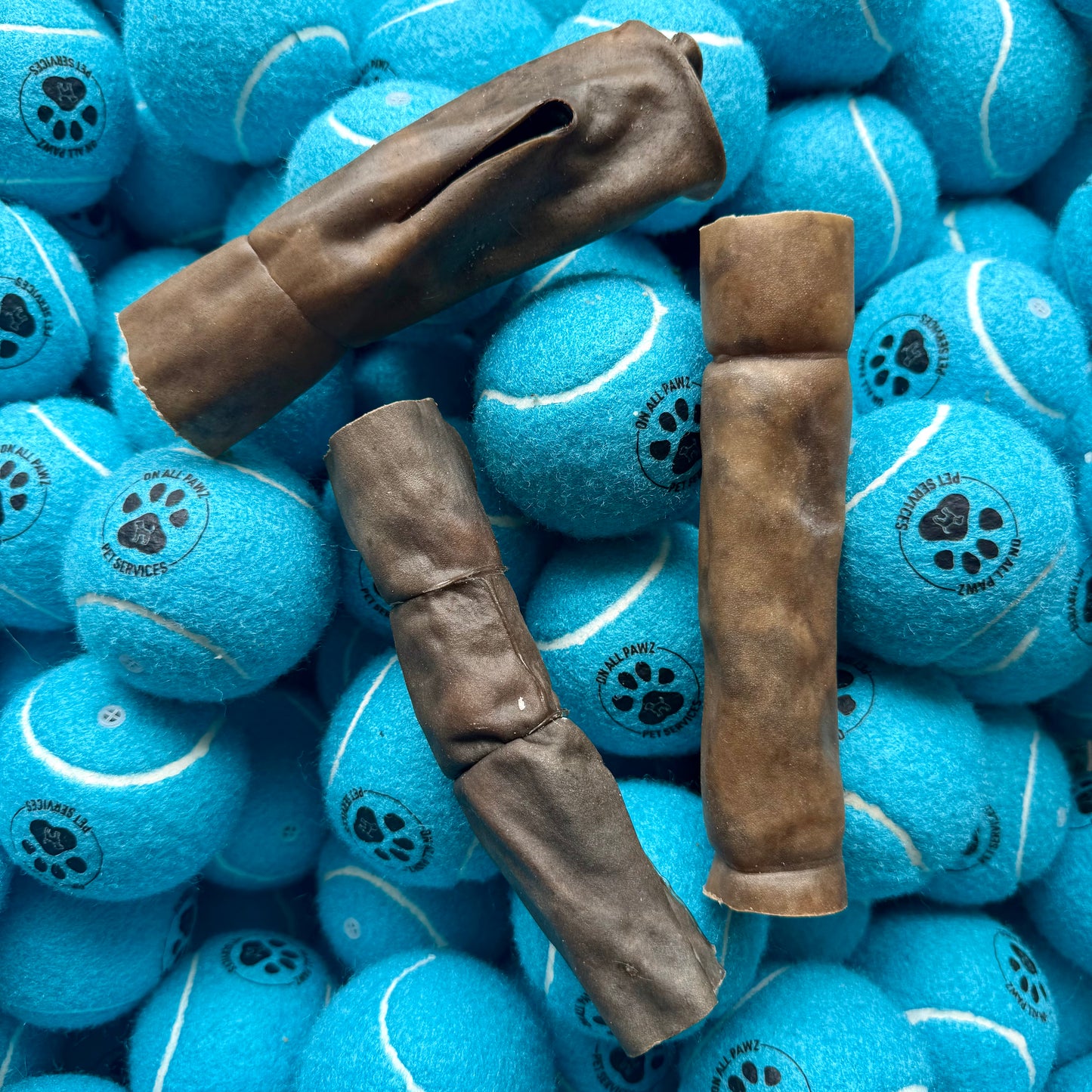 Blue tennis balls with paw prints and brown dog chew toys on top