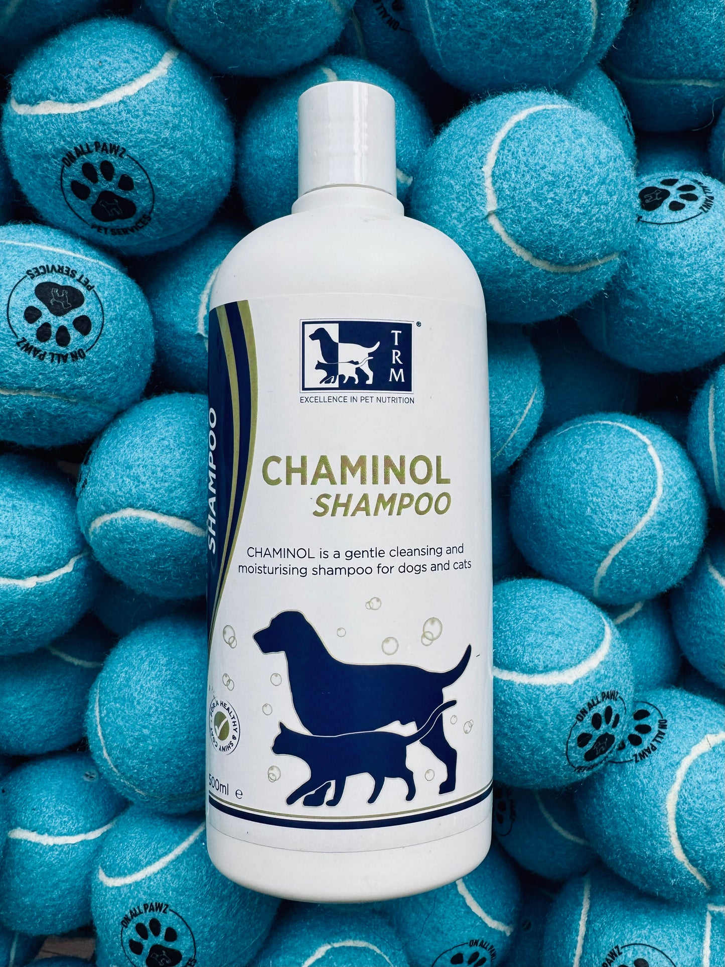 TRM Chaminol Shampoo bottle surrounded by blue tennis balls with paw prints.