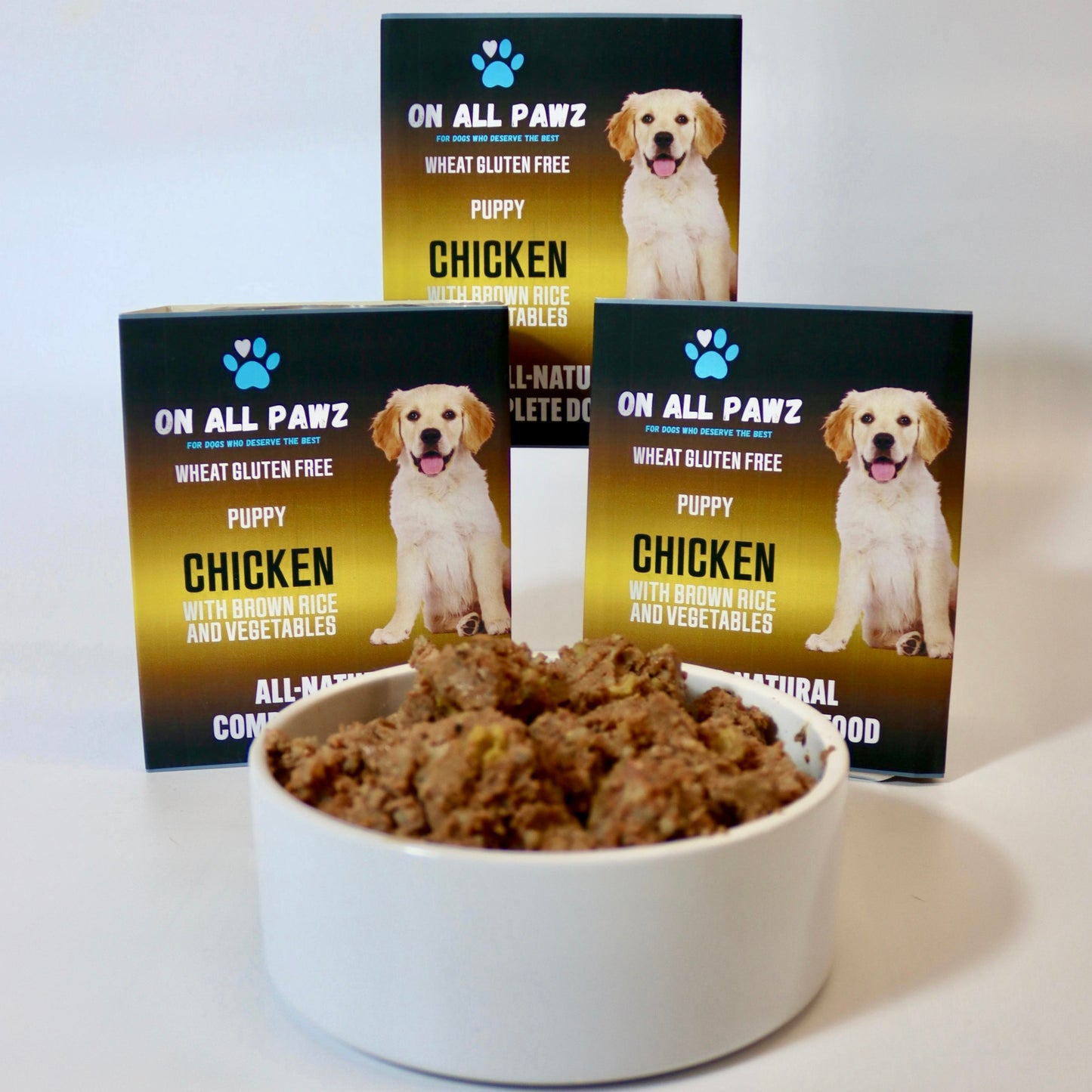 Bowl of dog food with 'On All Pawz' puppy chicken food packaging in the background.