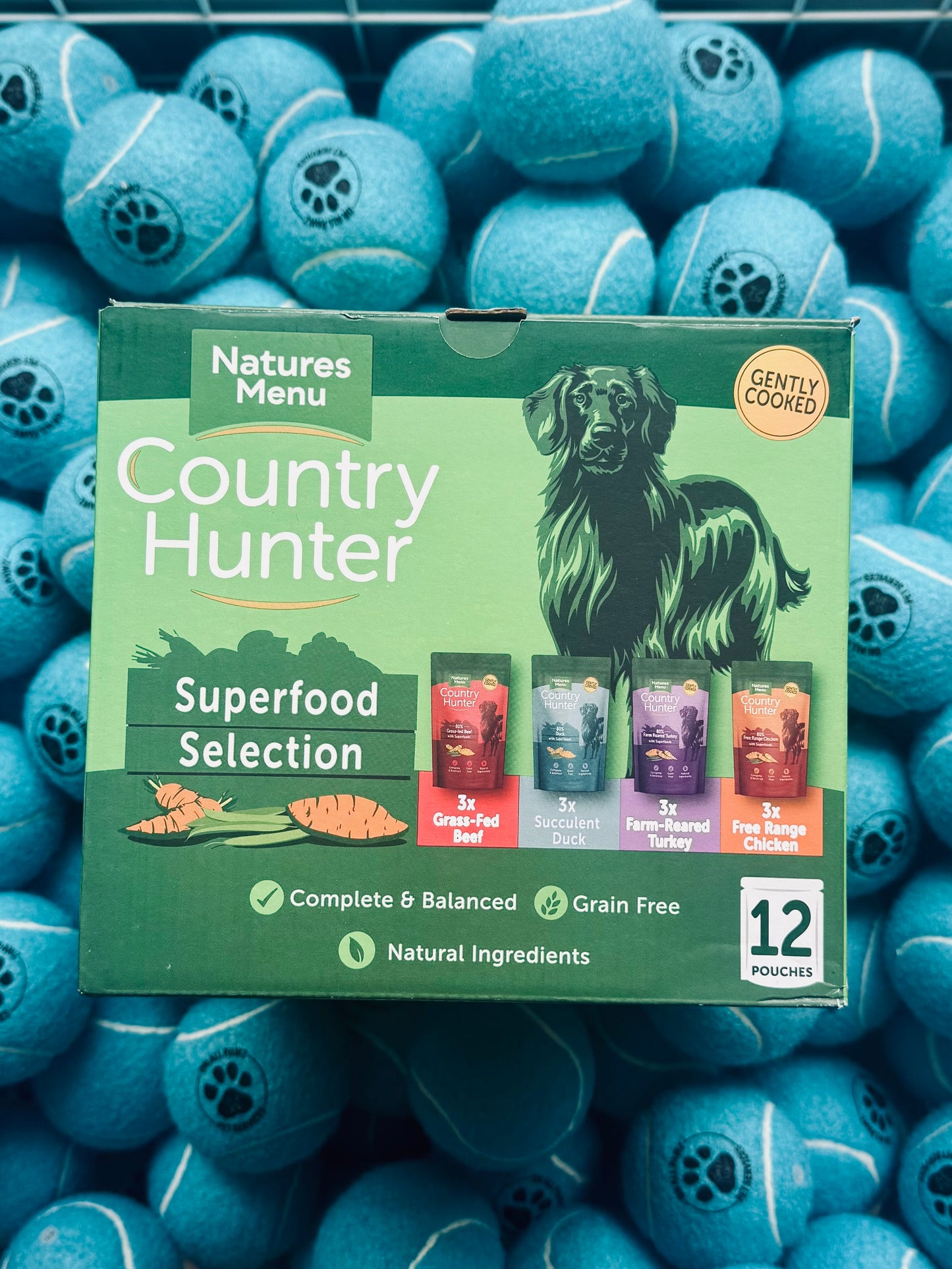 Natures Menu Country Hunter dog food packaging surrounded by blue tennis balls