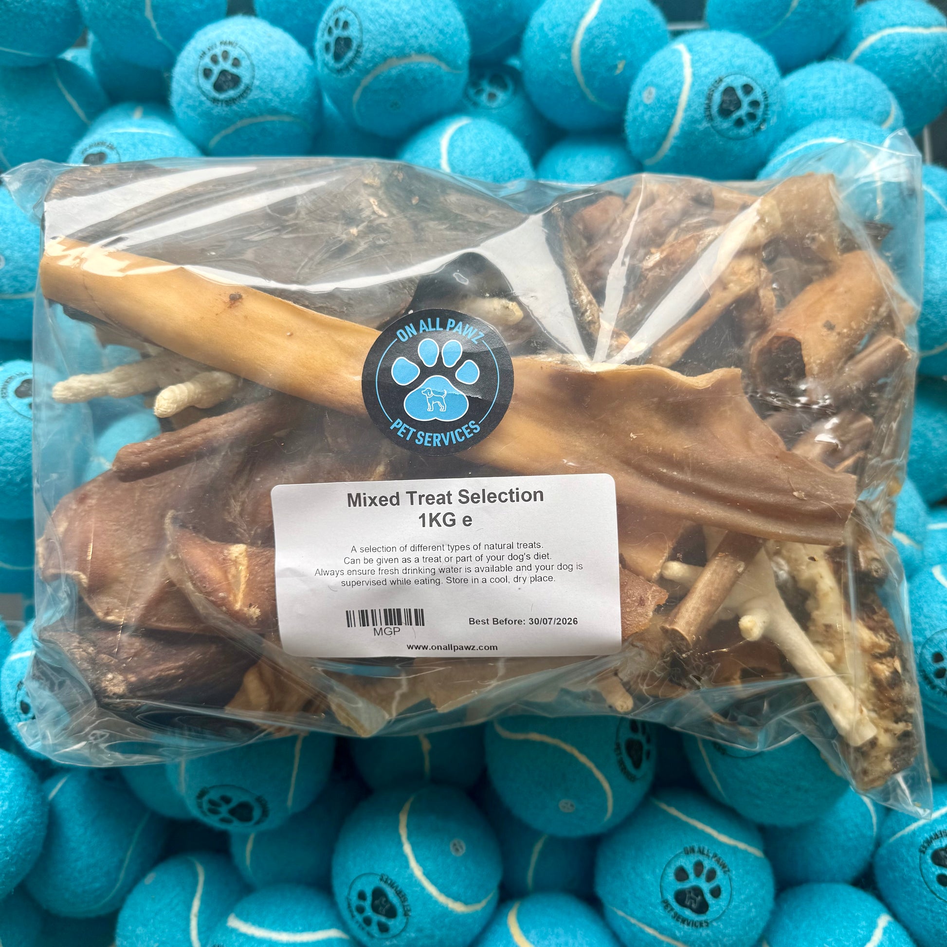 Bag of dog treats with a label on a background of blue tennis balls