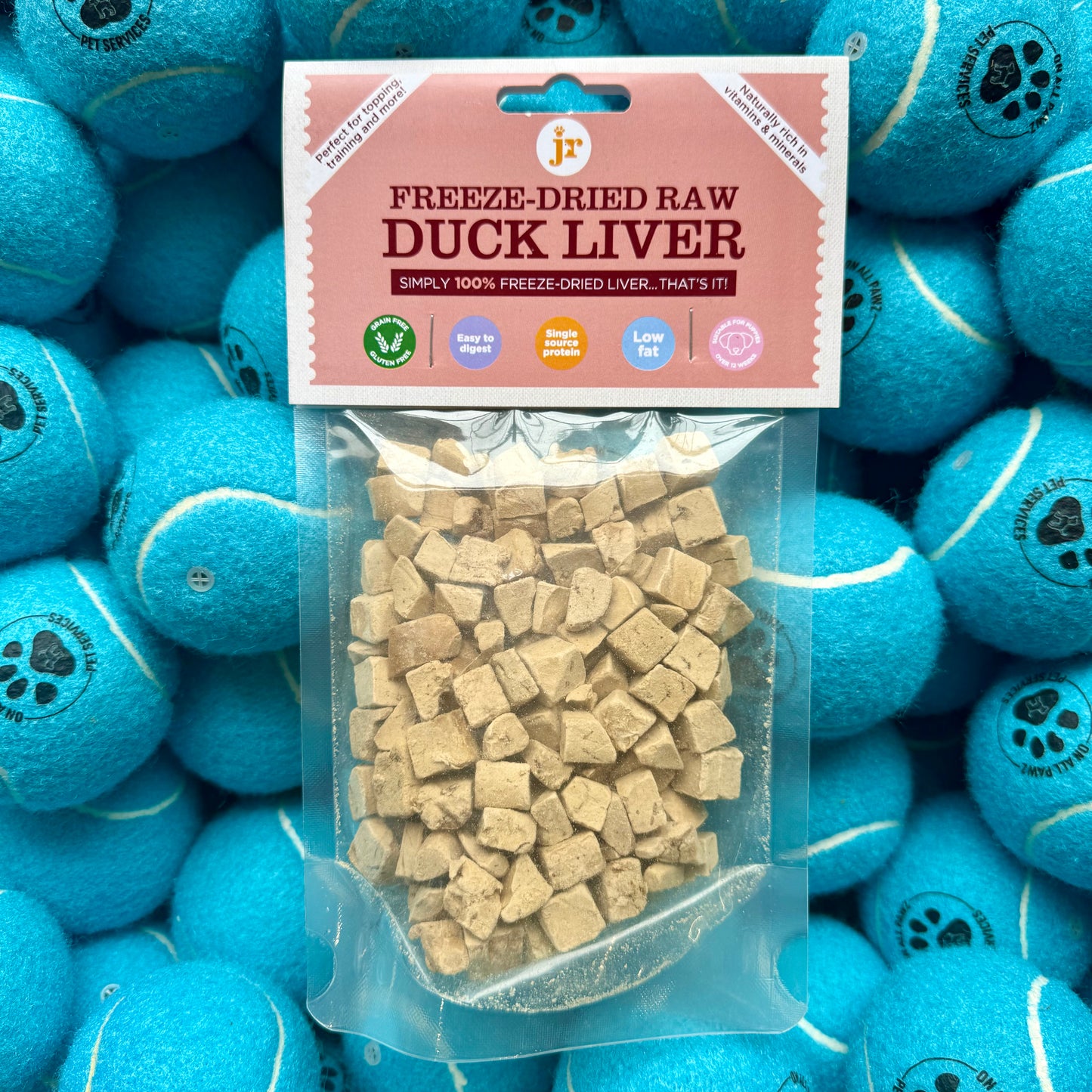 Packaged freeze-dried raw duck liver with a pink label on a background of blue tennis balls.