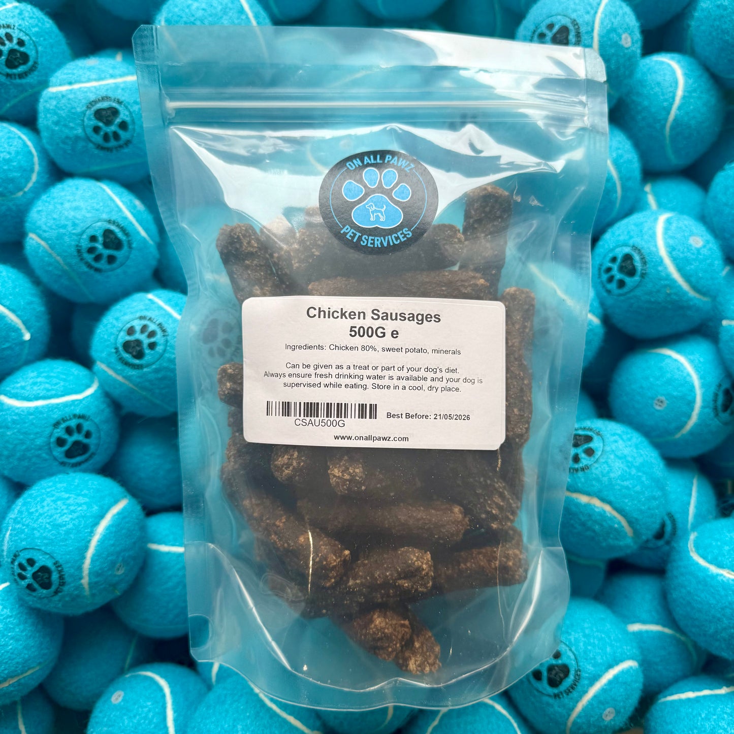 Package of chicken sausages with a label on a background of blue tennis balls