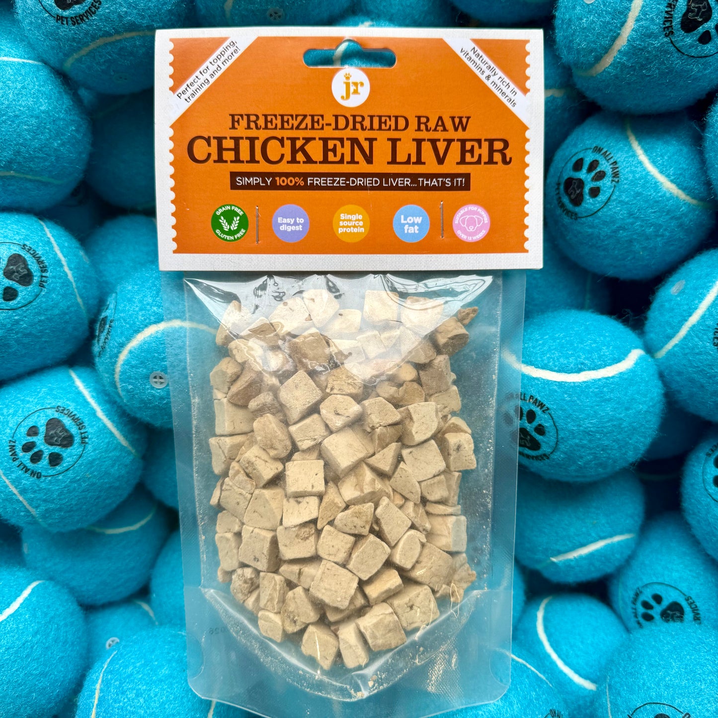 Freeze-dried raw chicken liver package with blue tennis balls in the background
