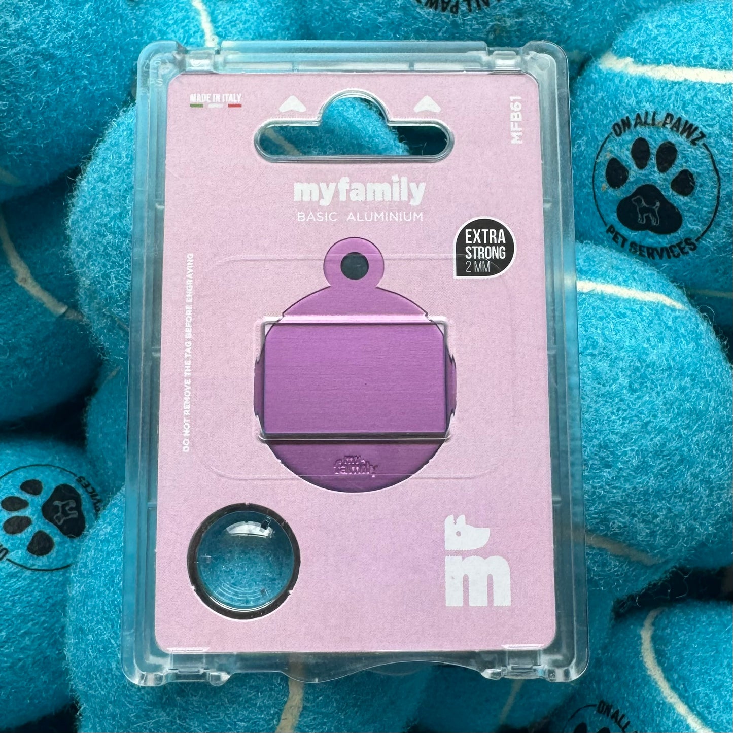 Purple pet tag in clear packaging on a blue plush background with paw prints.