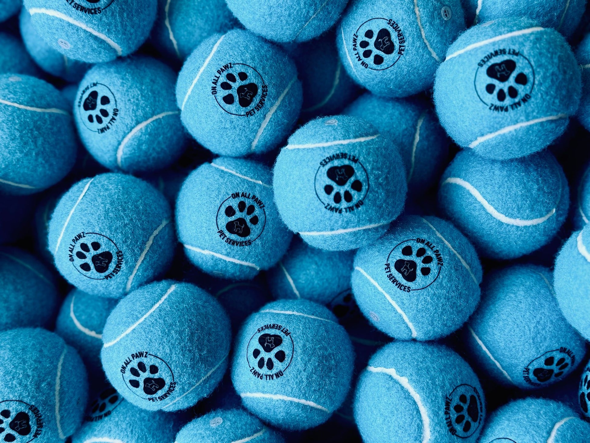 Multiple blue tennis balls with paw prints and text on a blue background