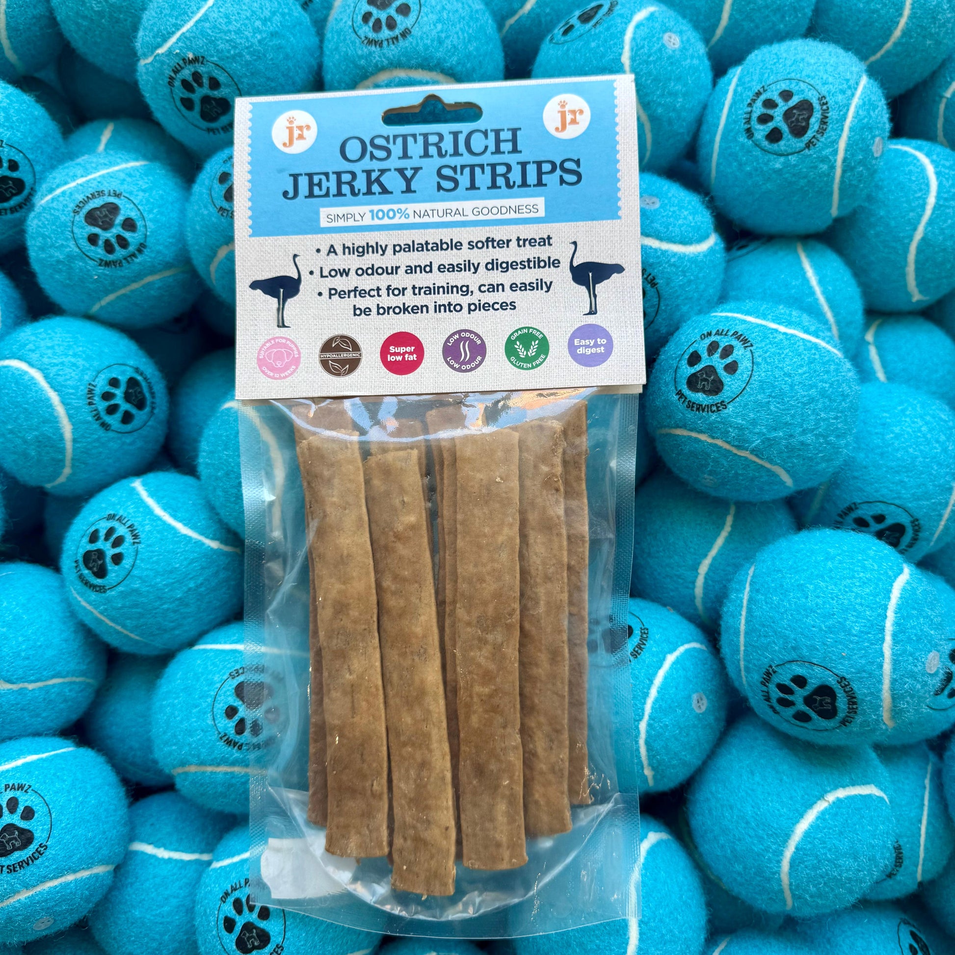 Ostrich jerky strips packaging with blue tennis balls in the background