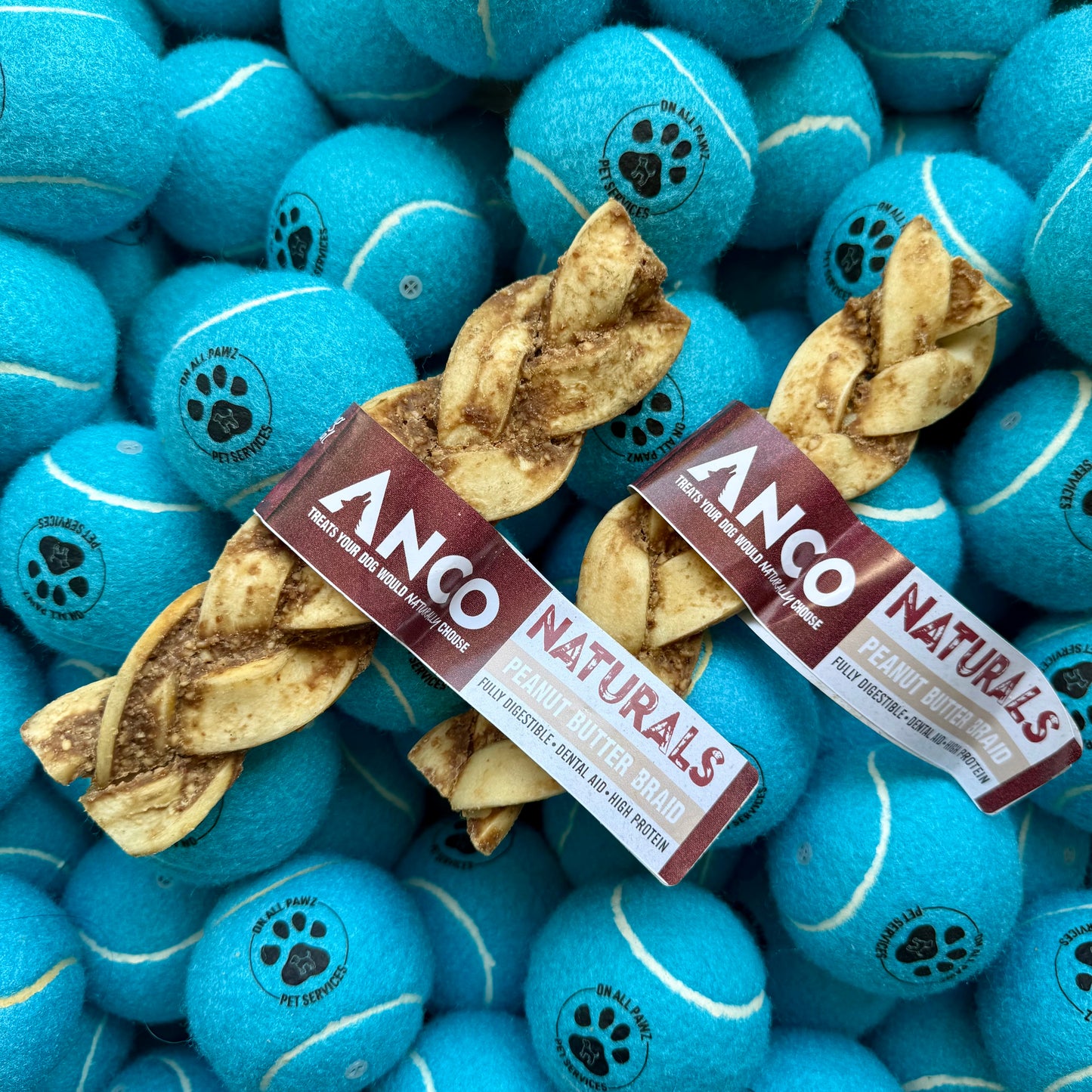 Dog chew treats and blue tennis balls with paw prints on a pile of blue tennis balls.