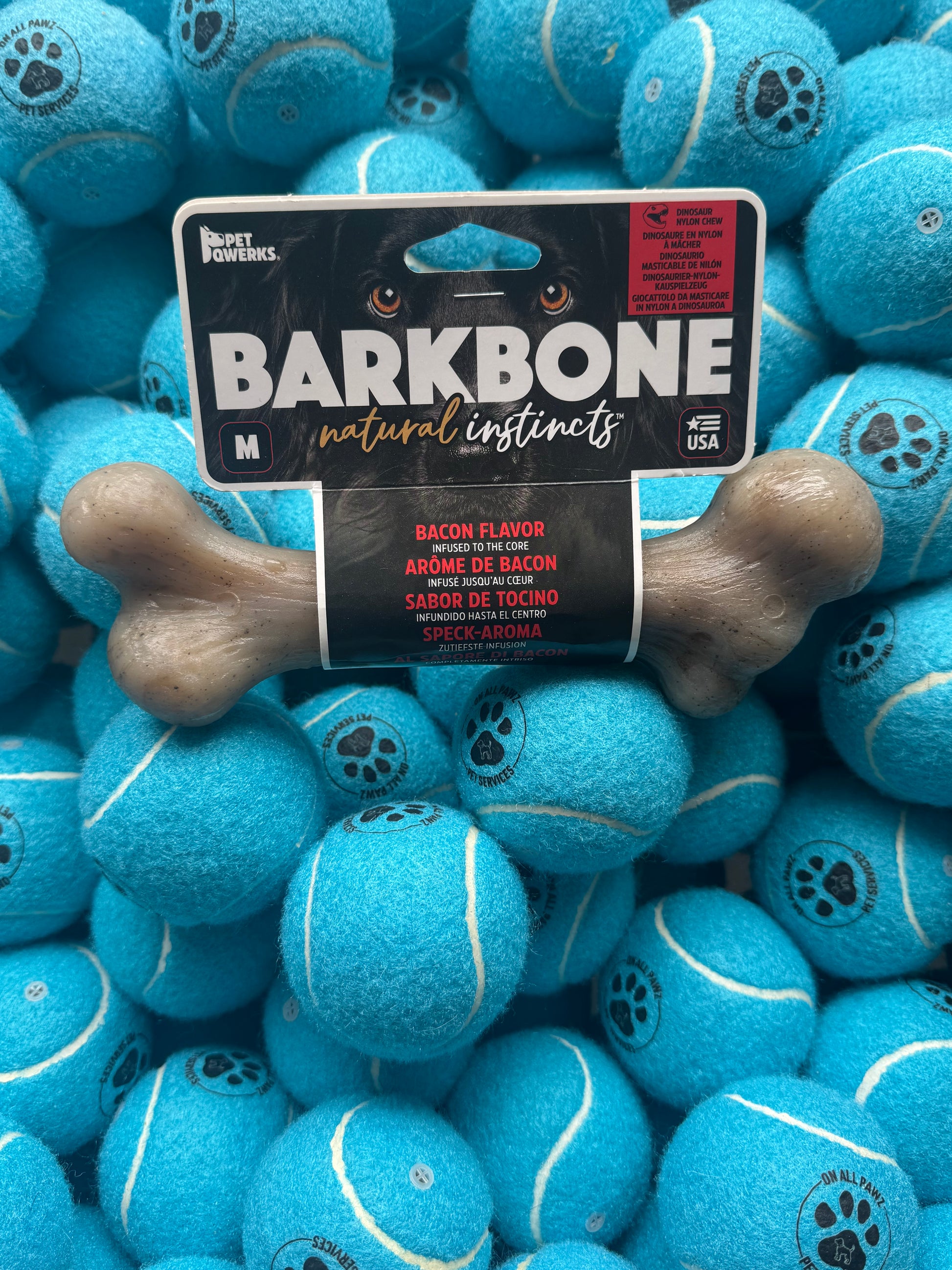 Dog chew toy with packaging on a pile of blue tennis balls