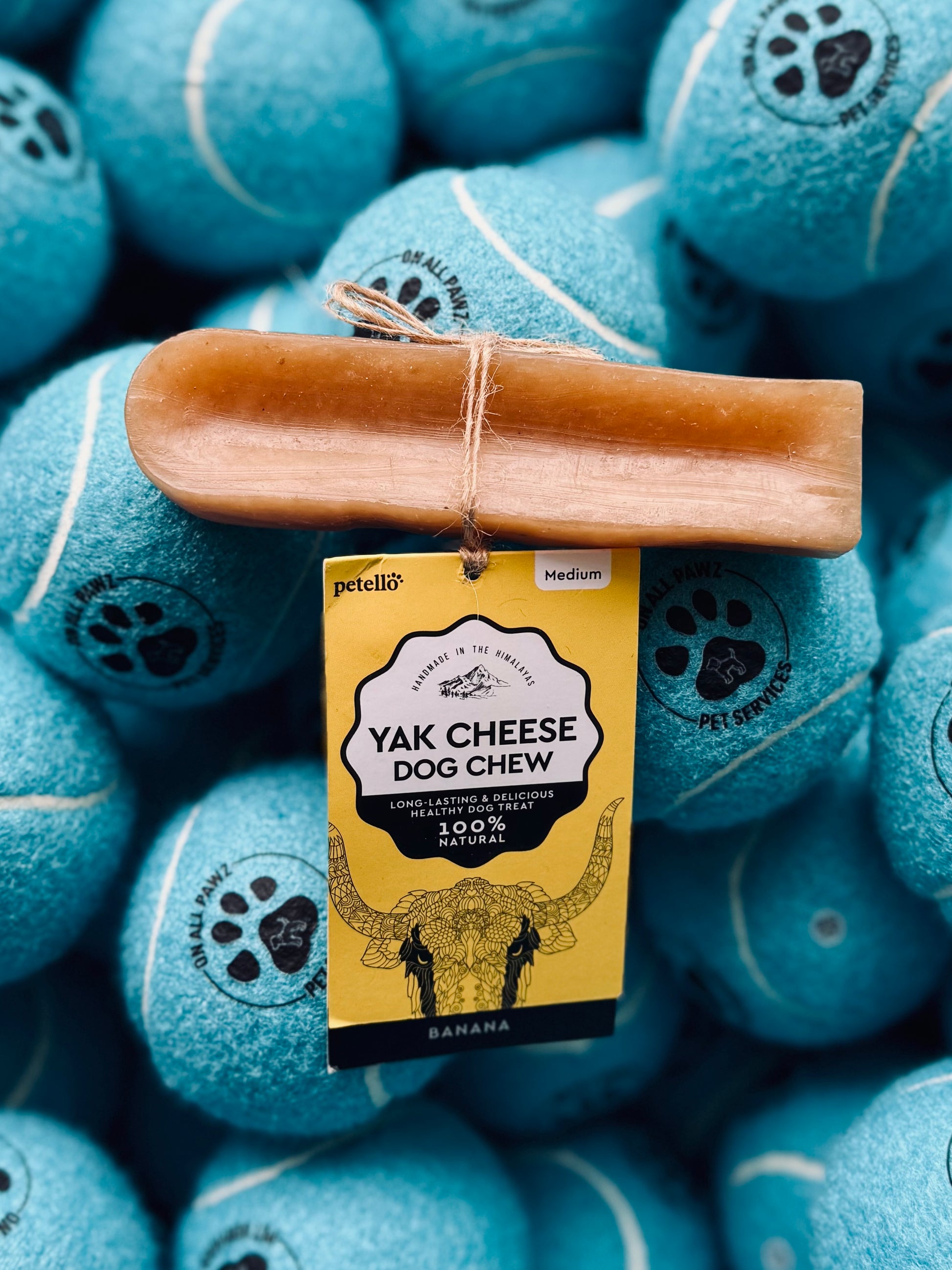 A yak cheese dog chew treat is displayed on top of a pile of blue dog toys, with a label showing details of the product.