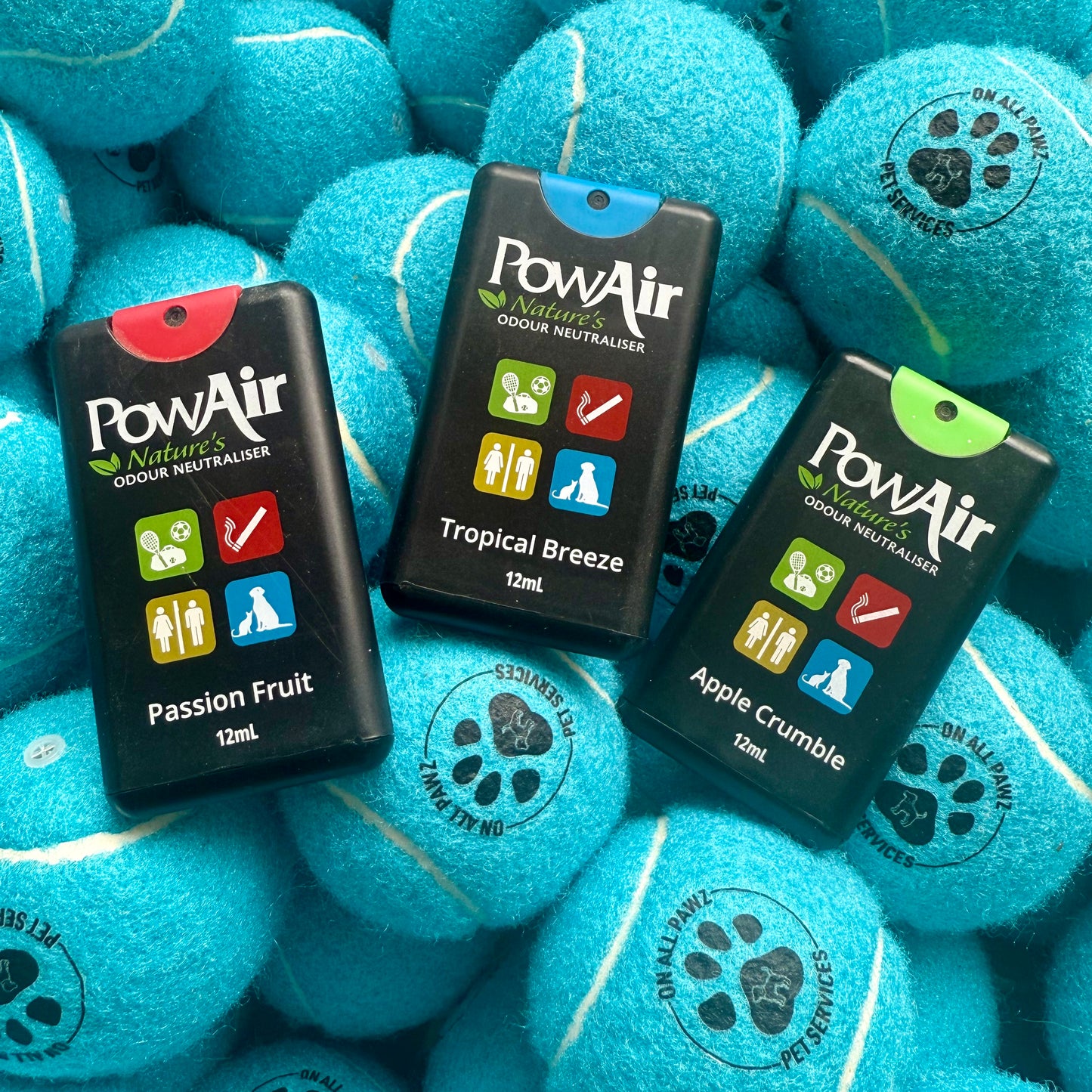 Three PowAir products on blue tennis balls with paw prints.