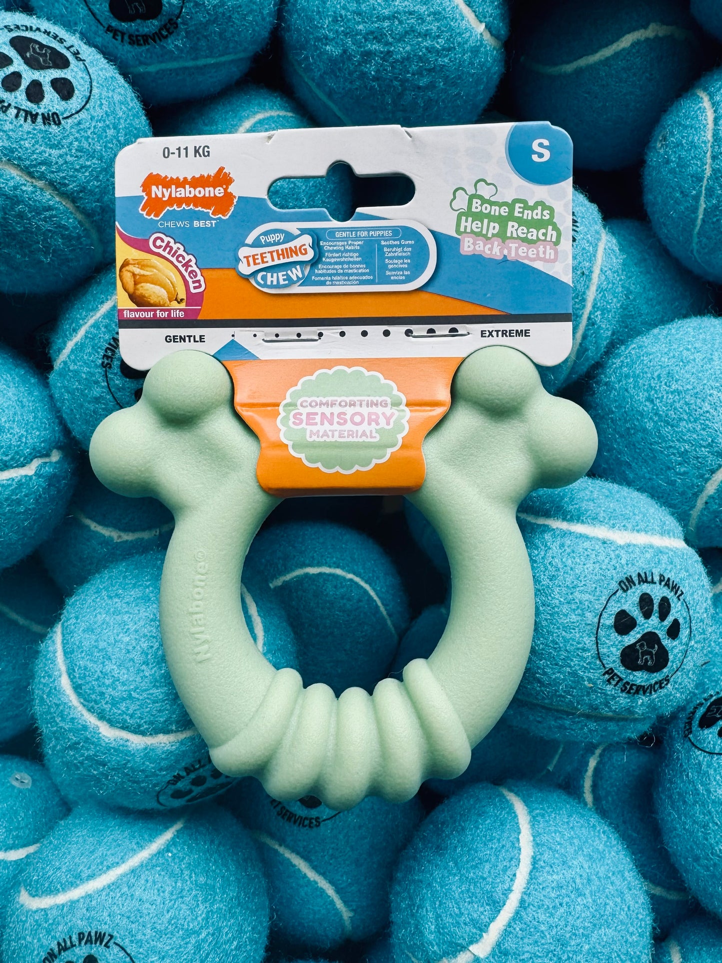 Teething ring with packaging on a background of blue tennis balls