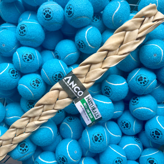 Blue tennis balls with a braided dog toy and 'Anco Naturals' label on a pile of balls.
