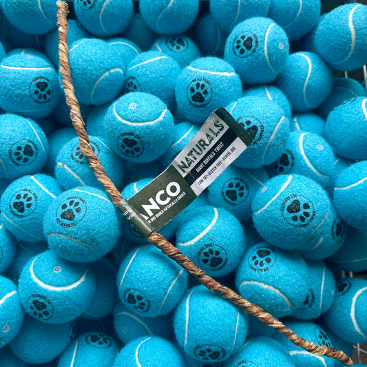 Blue tennis balls with paw prints and a NCO Naturals label, surrounded by more blue tennis balls.