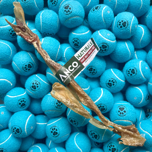Blue tennis balls with paw prints and a package of Anco Naturals dog chew on top.