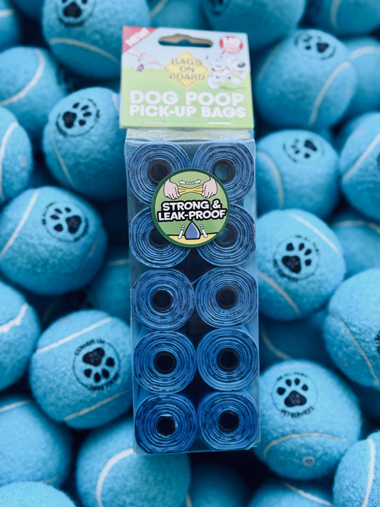 A pack of blue dog waste pickup bags displayed on a surface with multiple tennis balls.