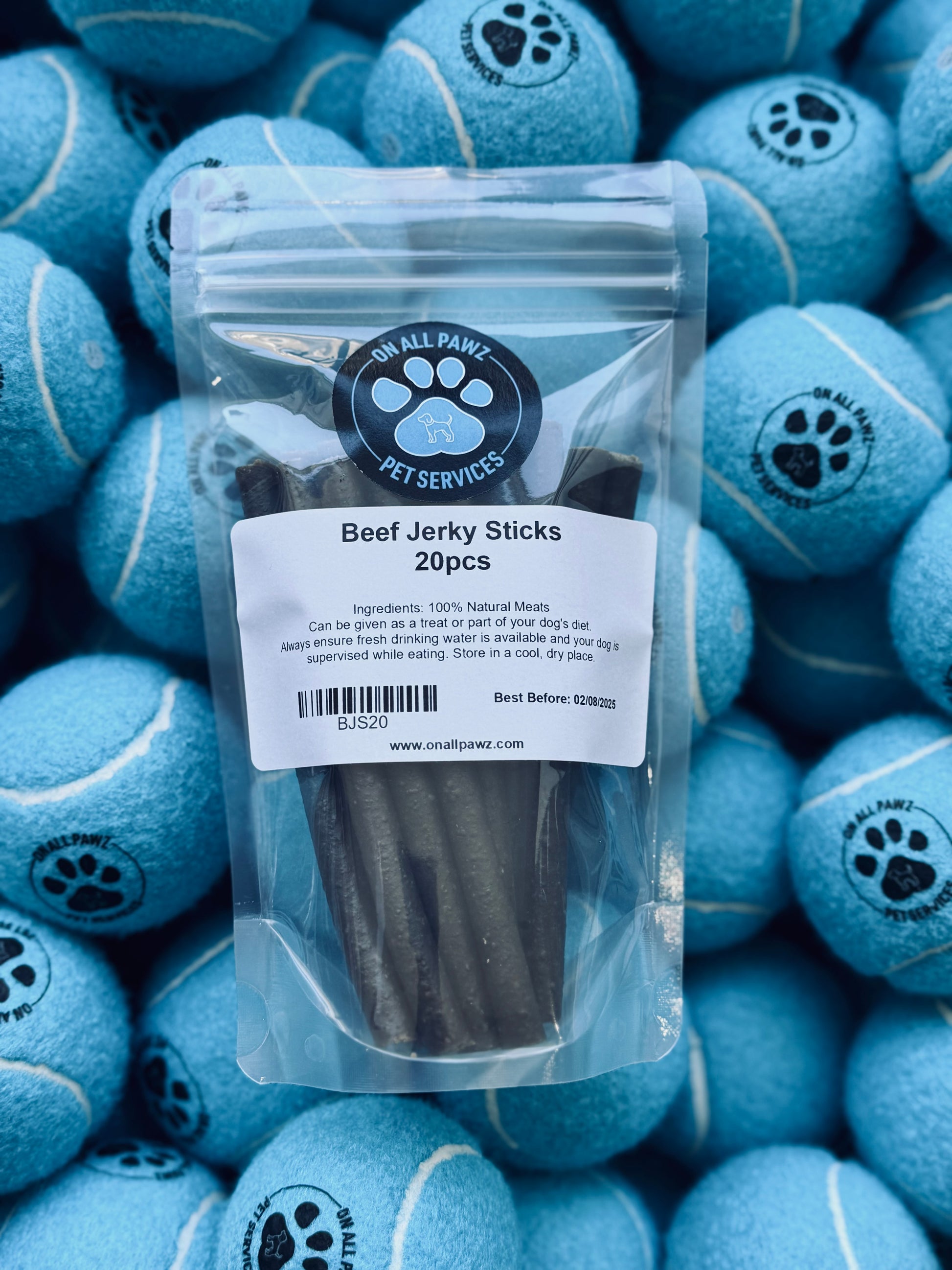A pack of beef jerky sticks in a transparent plastic packaging, placed on a background of blue dog toys with a paw print design.