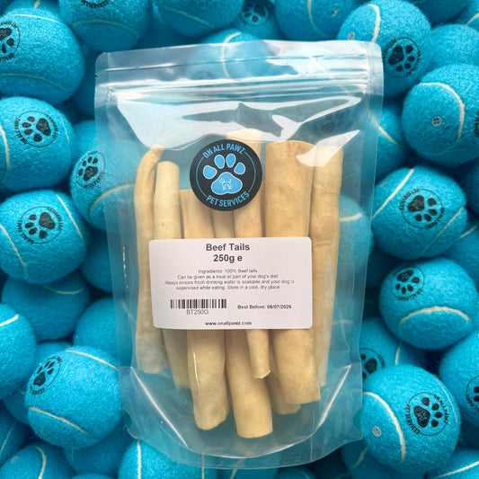 Packaged beef tails with a label on a background of blue tennis balls.