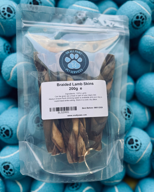 Packaged braided lamb skin dog treats displayed in front of a blue background with dog toys.