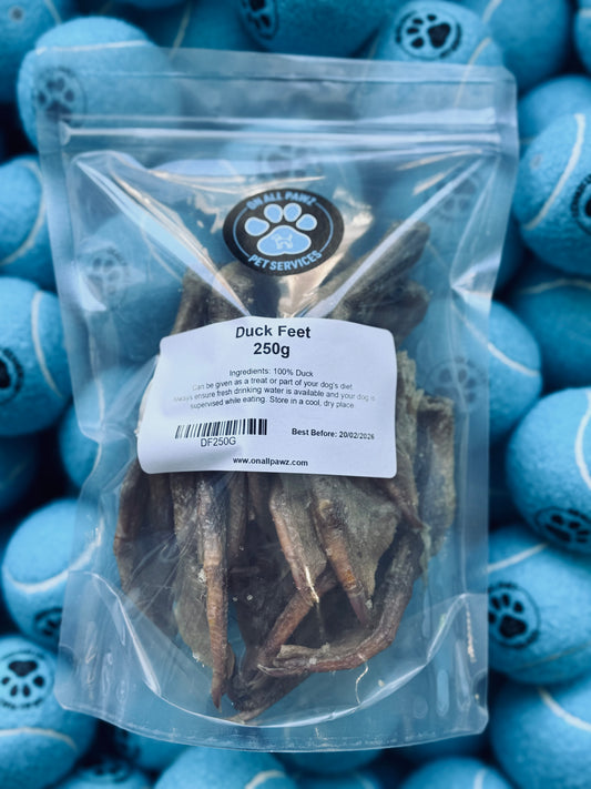 Packaged duck feet treats for dogs displayed against a backdrop of blue dog toys.