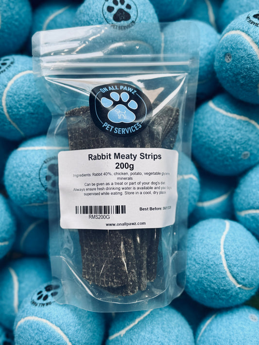 Packaging of Rabbit Meaty Strips 200g for dogs, displayed against a background of dog toys.