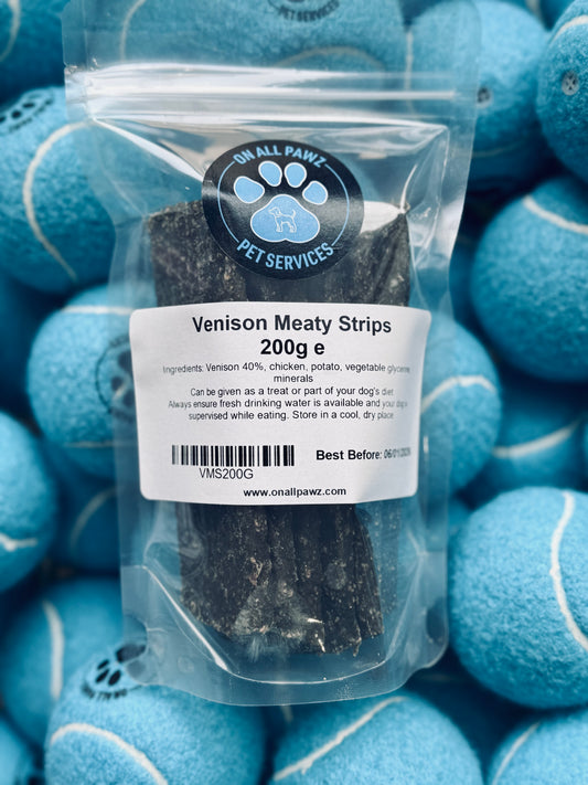 Packaging of Venison Meaty Strips dog treat, showing the product in a clear plastic bag with a label, placed on top of several tennis balls.