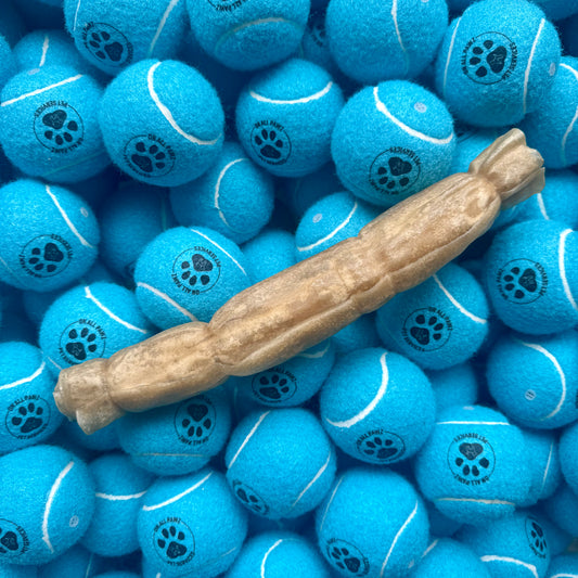 Blue tennis balls with paw prints and a brown dog chew toy on top