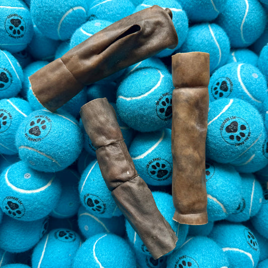 Blue tennis balls with paw prints and brown dog chew toys on top