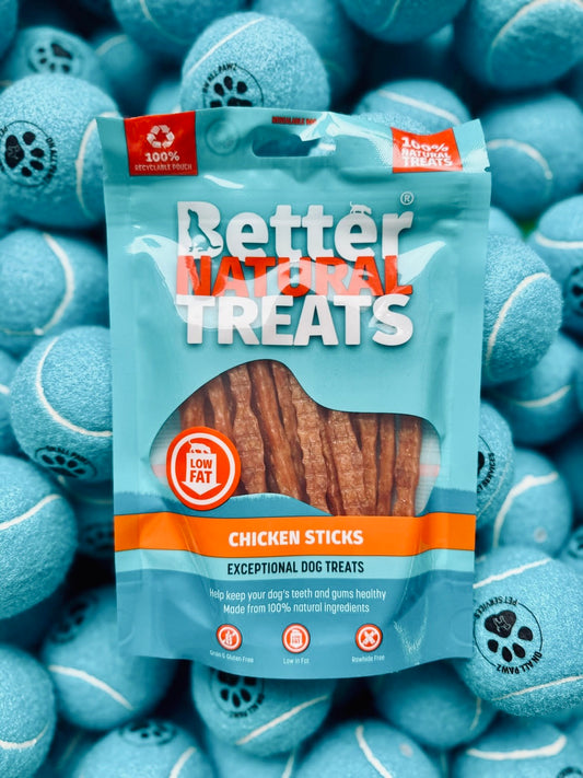 Package of Better Natural Treats Chicken Sticks for dogs surrounded by blue tennis balls.