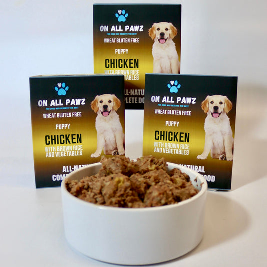 Bowl of dog food with 'On All Pawz' puppy chicken food packaging in the background.
