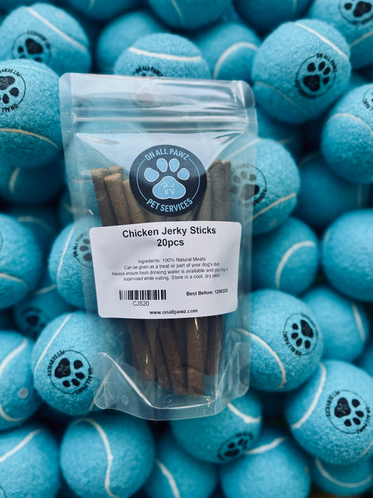 A clear plastic packaging containing chicken jerky sticks, labeled 'Chicken Jerky Sticks', placed on a background with blue tennis balls.