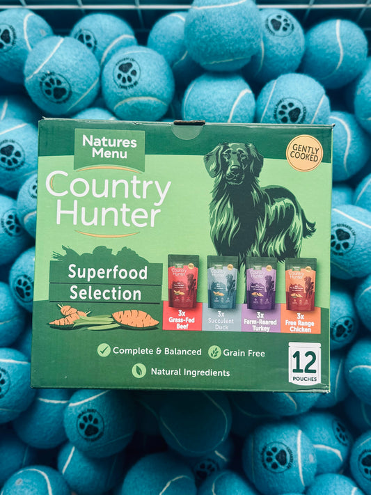 Natures Menu Country Hunter dog food packaging surrounded by blue tennis balls
