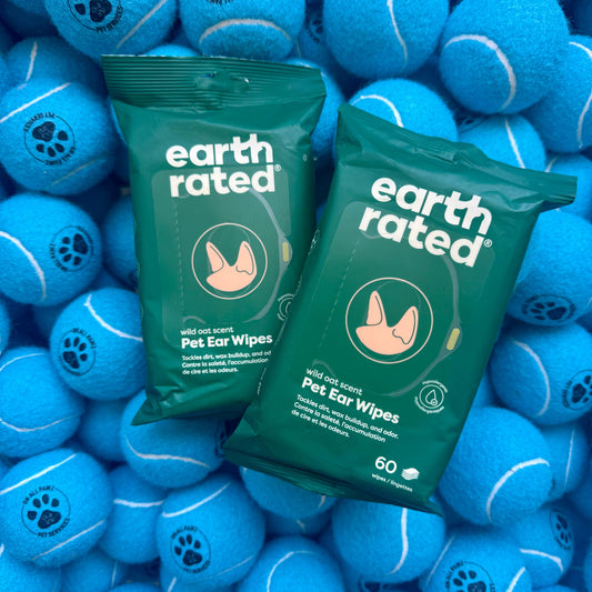 Two packages of Earth Rated pet ear wipes surrounded by blue tennis balls.
