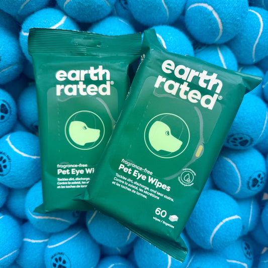 Two packages of Earth Rated Pet Eye Wipes on a background of blue tennis balls.
