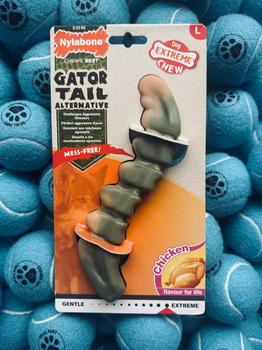 Nylabone Gator Tail dog chew toy packaging surrounded by blue tennis balls
