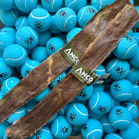Two pieces of ANCO dog chew treat on a background of blue tennis balls with paw prints.