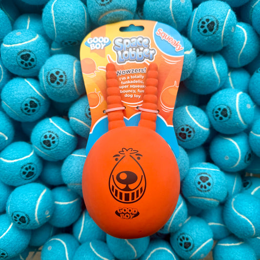 Orange Space Lobber toy with packaging on a background of blue tennis balls