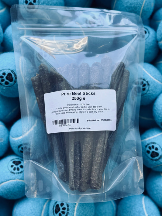 Packaged Pure Beef Sticks in a clear plastic bag with a label showing the product name and weight, placed on a background with blue dog treats shaped like bones.