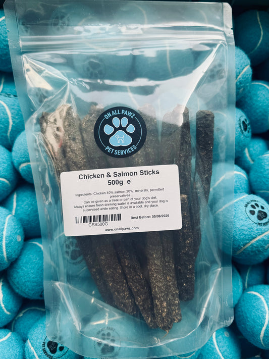 Package of Chicken & Salmon Sticks for pets with a visible brand label, surrounded by blue tennis balls.