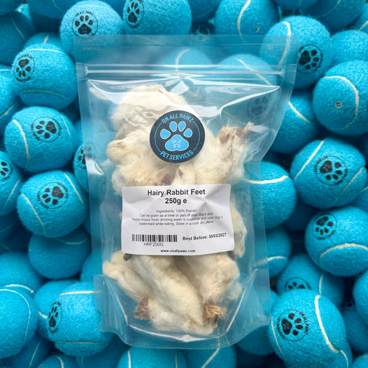 Package of Hairy Rabbit Feets with a background of blue tennis balls