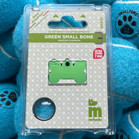 Green dog bone-shaped aluminum tag in packaging with blue balls in the background