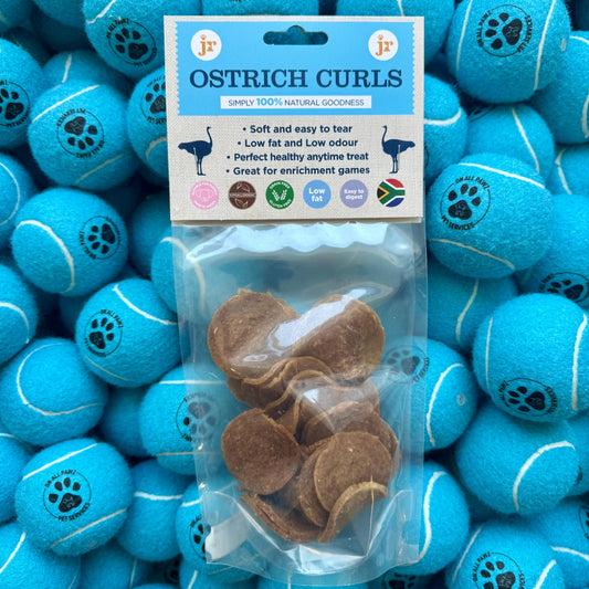 Blue Ostrich Curls dog treats with packaging on a background of blue tennis balls