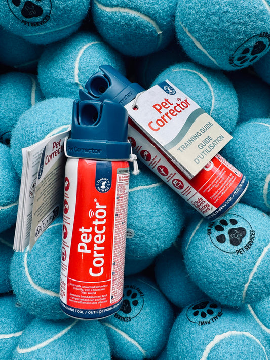 Two cans of Pet Corrector surrounded by blue tennis balls with pet brand logo.
