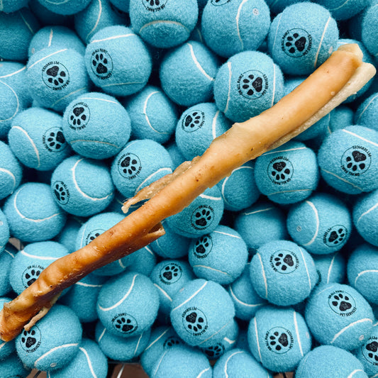 Blue tennis balls with paw prints and a chew stick on top