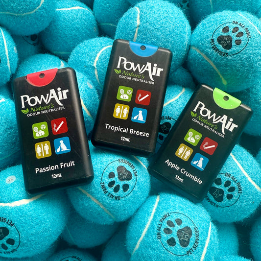 Three PowAir products on blue tennis balls with paw prints.
