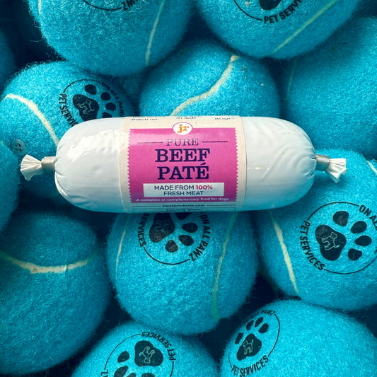 Roll of Pure Beef Páté on a pile of blue tennis balls with pet service branding.