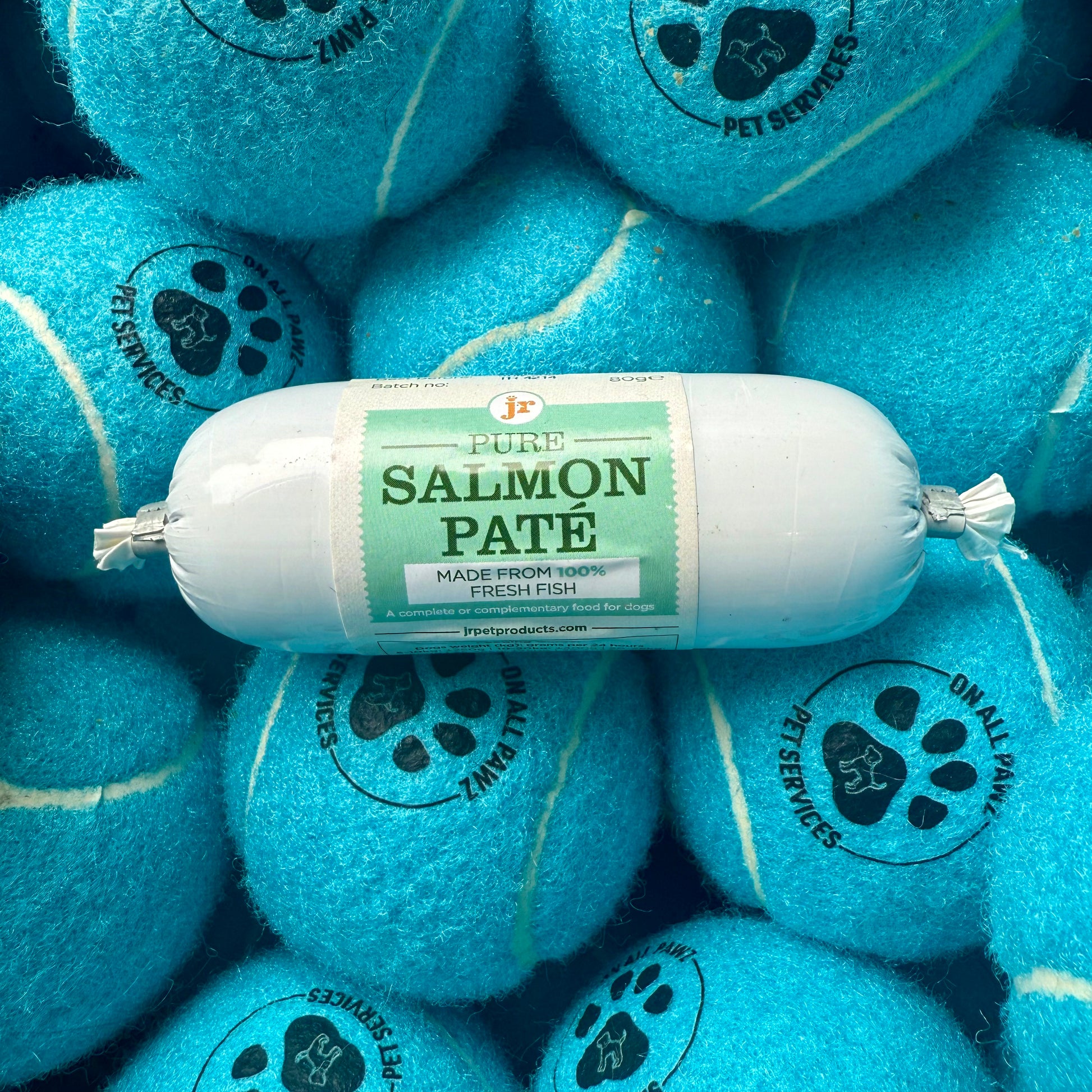 Salmon pate package surrounded by blue tennis balls with pet service logos.